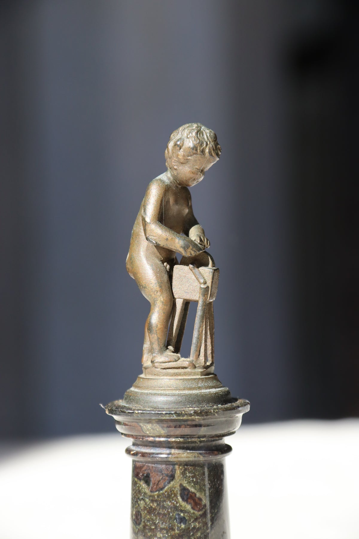 Miniature Bronze Figurine of Cupid Sharpening His Points on Marble Pedestal