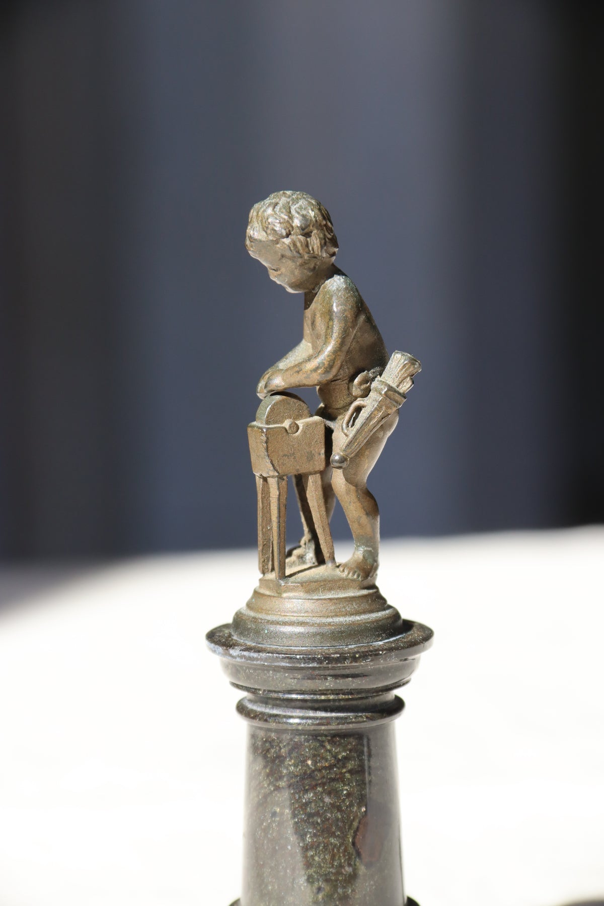 Miniature Bronze Figurine of Cupid Sharpening His Points on Marble Pedestal