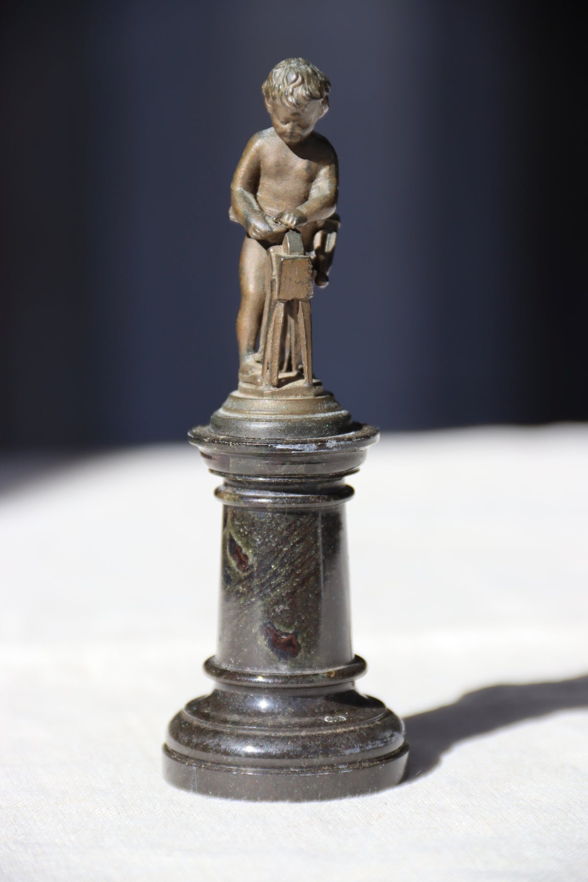 Miniature Bronze Figurine of Cupid Sharpening His Points on Marble Pedestal